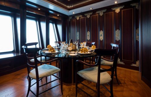 Interior formal dining area with circular table and dark wood onboard charter yacht BOADICEA