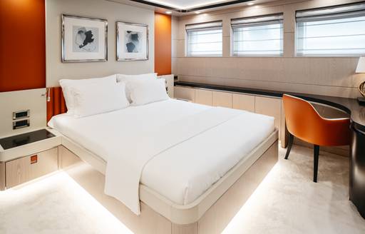 Double guest cabin with central berth and an orange seat onboard charter yacht HEEUS