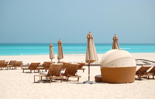 Sandy beach with closed parasols and sun loungers