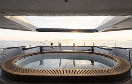 Close up view of the ondeck Jacuzzi onboard charter yacht MALIA, with a female charter guest in the background enjoying the view