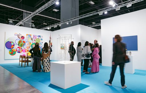 Exibit at Art Basel Miami with large painting and sculpture center, with visitors looking