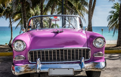 pink vintage car on the beach in cuba