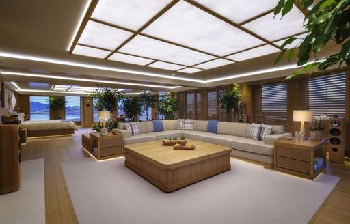 Interior lounge area with L-shaped seating and a large coffee table onboard superyacht charter FLYING FOX