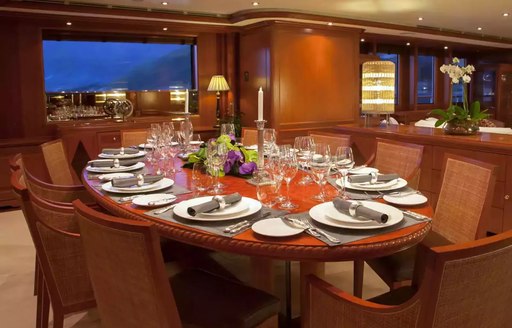 Formal dining setup onboard charter yacht JO I with glazing in the background