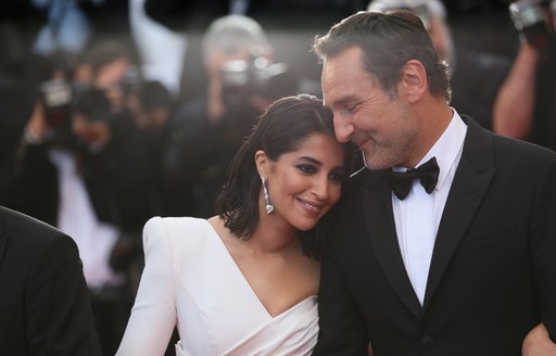 actress wearing white lays her head on shoulder of actor at cannes film festival