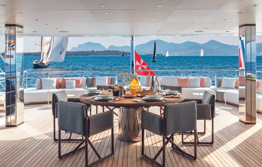 Alfresco dining area onboard charter yacht RIO, circular table set for a meal and chairs 