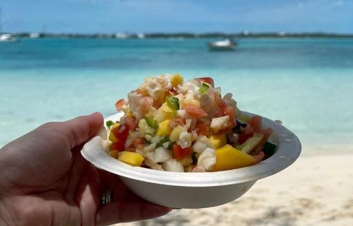 Hand holding a conch salad prepared on the beach by Chat N Chill restaurant 