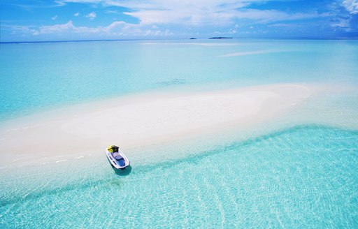 Landscape seascape aerial view over Maldives Male Atoll sandbank island. Jet ski at the white sandy beach