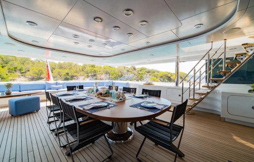 Exterior dining area with long table surrounded by chairs onboard charter yacht HOLDIN' MY OWN