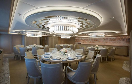 Formal dining room with four elaborate circular tables and a chandelier