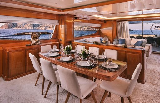 Interior dining area onboard charter yacht ELVI, long table with eight surrounding chairs and extensive glazing