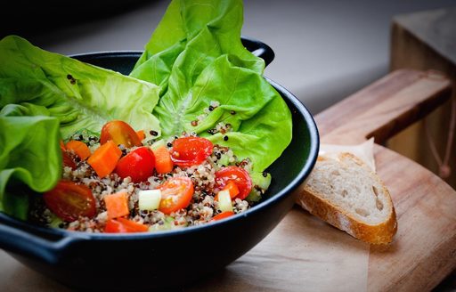 A tomato and lettuce salad on a wooden chopping board with a slice of bread