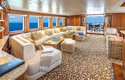 Overview of the interiors onboard charter yacht ASTERIA, with plush sofas surrounded by large windows 