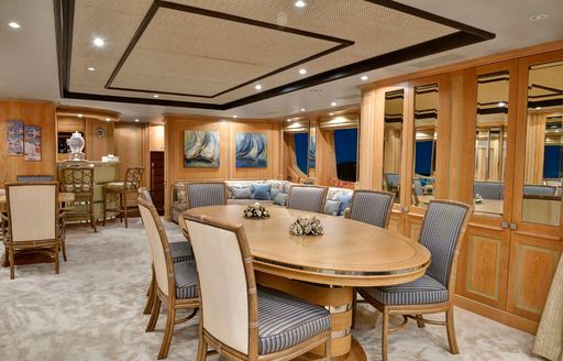 Long dining table and seats in the main salon of charter yacht QUEST R