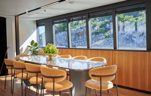 Interior dining area with table and yellow seats onboard yacht rental MARALLURE