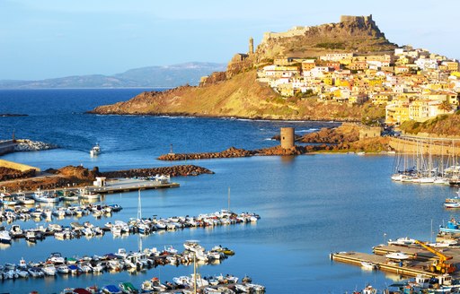 yacht harbour with citadel on a hilltop in the background in sardinia