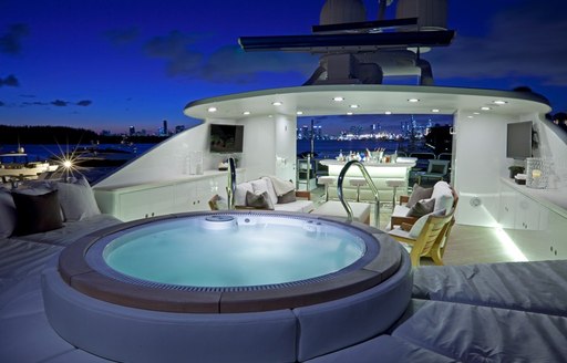 night shot of lit-up jacuzzi pool on superyacht alessandra, with bar and seating in background