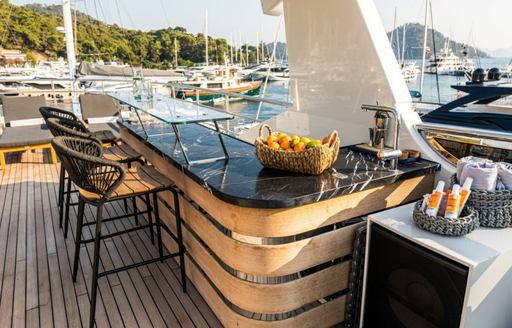 Exterior wet bar with black stools onboard charter yacht ZEEMAR