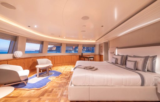 Master cabin onboard charter yacht CARINTHIA VII, central berth facing forward with multiple windows and two armchairs