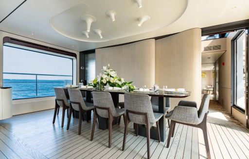 Interior dining table and gray seats onboard charter yacht MIKOH