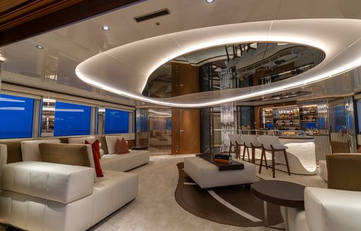 Overview of the upper salon onboard charter yacht ETERNAL SPARK with white seating to port side and a wet bar starboard