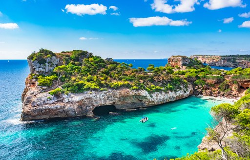 Small motor yacht anchored in blue waters of Ibiza