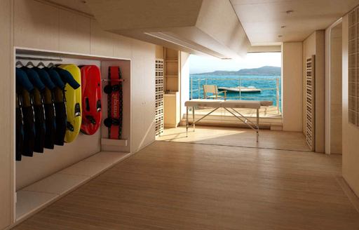 Fold-down balcony with a massage table and watersports equipment in the foreground onboard superyacht charter O'MADELEINE