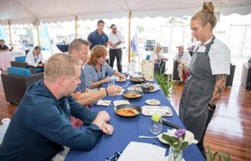 Superyacht chef at table with judges looking at dishes