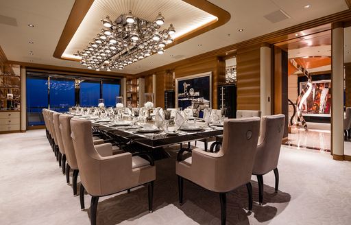 Interior dining area with long table set for a meal onboard charter yacht MAR
