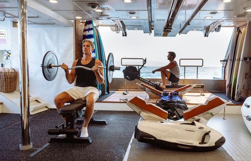 Charter yacht GALILEO charter guests using gym equipment in beach club