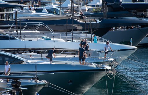 Superyachts berthed at the Cannes Yachting Festival with crew on deck