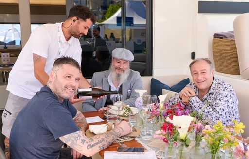 Judges sat at table on superyacht being served drinks