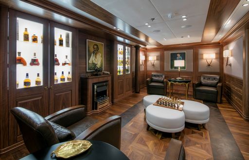 Interior seating area with brown armchairs and a games table onboard charter yacht KATINA