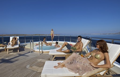 Guests gathered around the Jacuzzi on board luxury yacht O'MEGA