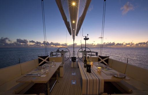 cockpit for sailing yacht PTARMIGAN is set for dinner as the sun sets over the horizon