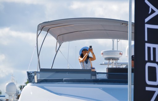 Woman captures image at FLIBS from sundeck of yacht