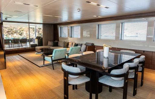 Interior dining area with black table and multiple windows onboard charter yacht ZEEMAR