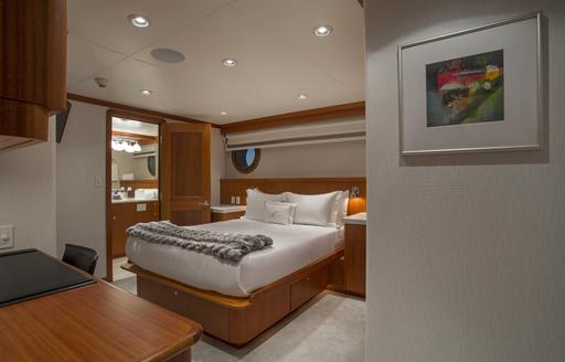 Double bed in cabin on explorer yacht MARCATO, with wooden detailing and door to ensuite open