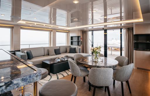 Interior seating area with circular table and gray seats onboard charter yacht HEEUS
