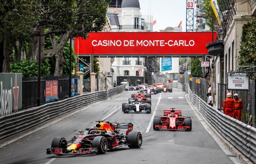 Head-on view of racecars as they speed down the track below Monte Carlo banners at the Formula One Monaco Grand Prix