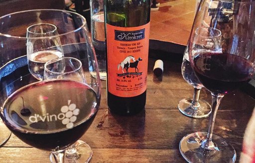 Local red wine in glasses with the bottle adorn a wooden table in Dubrovnik, Croatia