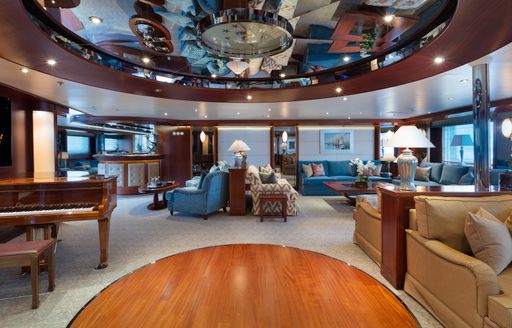 spacious main salon with grand piano and seating on board charter yacht ‘Lauren L’ 