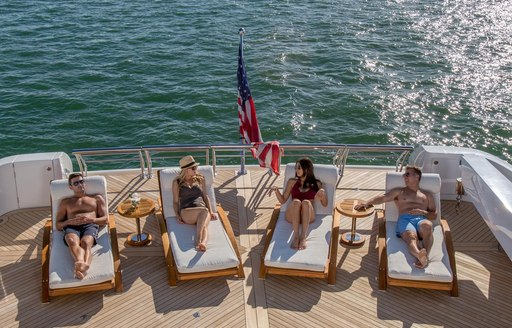 two couples relaxing on sunloungers onboard luxury charter yacht USHER 