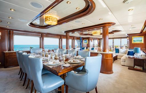 Charter yacht AQUASITION interior dining table with blue chairs and large windows