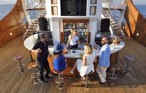 Charter guests around the alfresco bar on superyacht Christina O