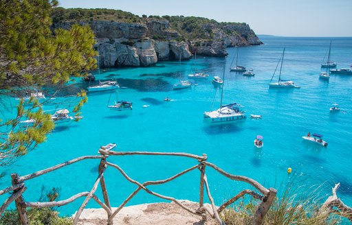 Bright blue bay in Spain, with several charter yachts at anchor