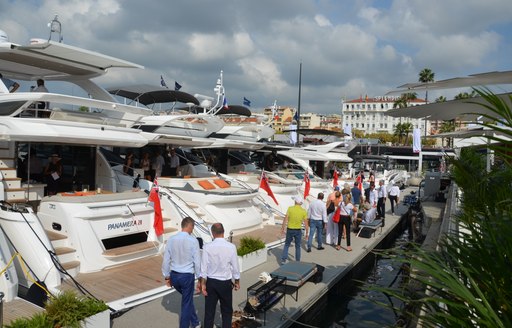 People walk past luxury yachts at Cannes Yachting Festival