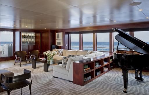 Interior lounge area with plush sofa and a grand piano onboard yacht charter CYAN