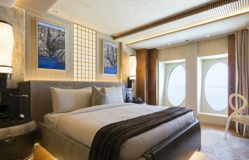 Double guest cabin onboard yacht charter NIRVANA. Central double berth with bedside tables and a dressing table next to window.