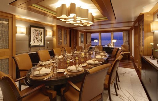 Overview of the dining room onboard charter yacht LADY BRITT, central dning table with ornate decoration and a window in the background